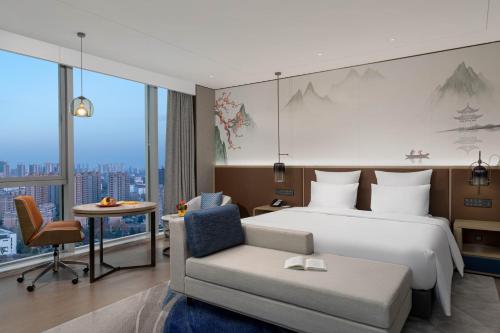 a bedroom with a bed and a couch and a chair at Pullman Huai'an in Huai'an