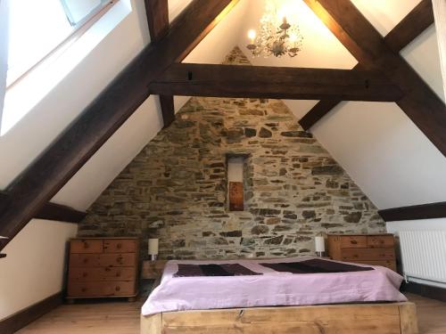 a bedroom in an attic with a stone wall at Peregrine hall in Lostwithiel