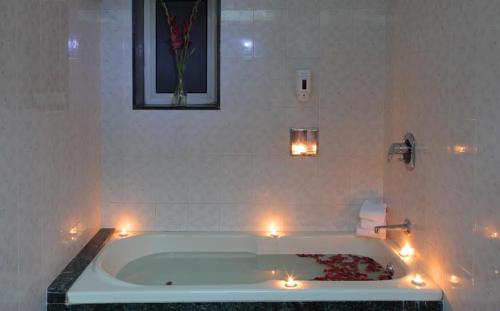 a bathroom with a tub with candles in it at Hiltop Hotel in Mumbai