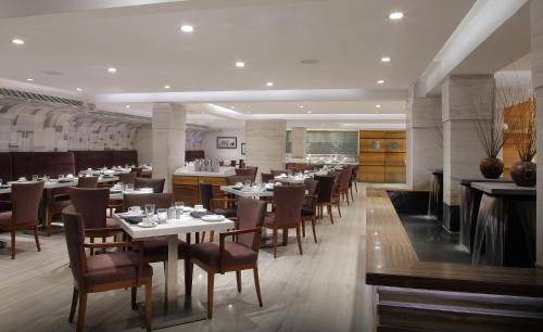 un ristorante con tavoli e sedie in una stanza di Hiltop Hotel a Mumbai