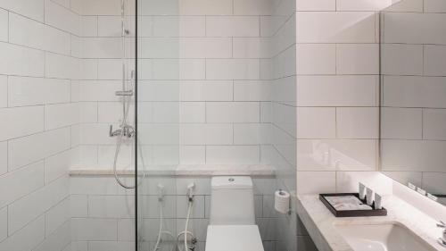 a bathroom with a shower and a toilet and a sink at Veranda Hotel Pakubuwono in Jakarta