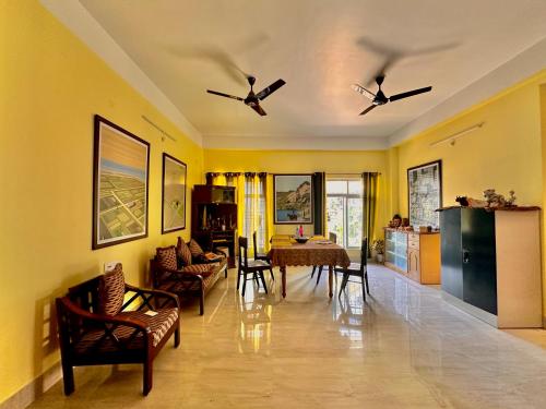 a living room with yellow walls and a table and chairs at Three Little Birds Homestay in Guwahati