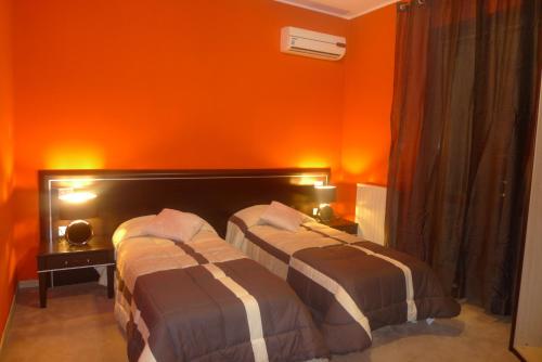 two beds in a room with an orange wall at B&B Bed& Fly - Mamma Mia in Azzano San Paolo