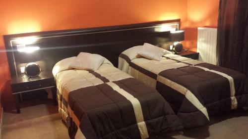 two beds in a hotel room with orange walls at B&B Bed& Fly - Mamma Mia in Azzano San Paolo