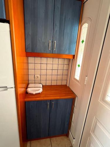 Elle comprend une petite cuisine avec des placards bleus et une fenêtre. dans l'établissement Καλοκαιρινό σπίτι δίπλα στη θάλασσα, à Gialiskari