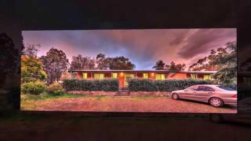 a tv screen with a car parked in front of a house at Sandy Hollow Tourist Retreat in Sandy Hollow