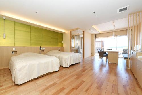 ein Hotelzimmer mit 2 Betten und einem Schreibtisch in der Unterkunft Shimoda Yamatokan in Shimoda