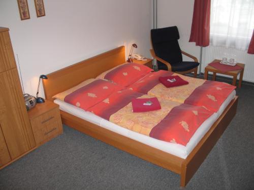 a bedroom with a bed with red sheets and a chair at Pension Zlata Noha in Bratislava