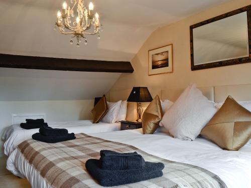 two beds in a hotel room with towels on them at Dolls Cottage in Bourton on the Water