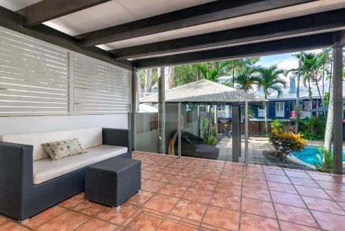 an outdoor patio with a couch and an umbrella at Paradise On The Beach Resort in Palm Cove