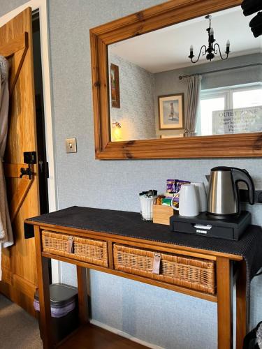 a counter with a mirror and a table with a tea kettle at Woodbriar in Conwy