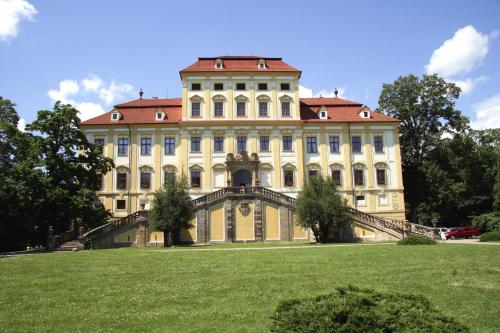 a large building with a staircase in front of a grass field at Zamek Cerveny Hradek in Jirkov