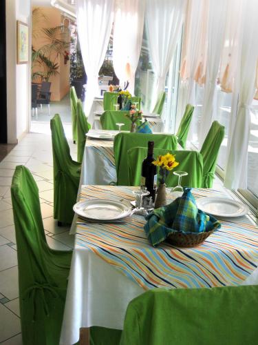 a restaurant with green tables and chairs with flowers on them at HOTEL SILVANA in Cattolica