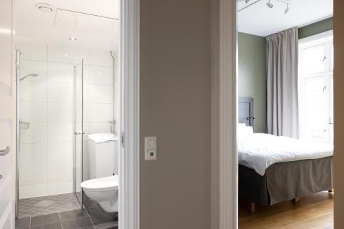 a bathroom with a shower and a toilet and a bed at Frogner House - Bislett in Oslo