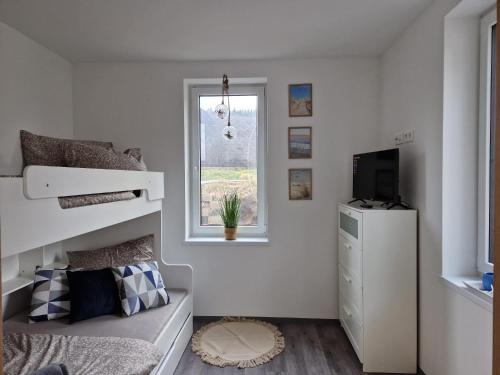 a white bedroom with a bunk bed and a window at Apartmán Jestřábí Lipno in Černá v Pošumaví