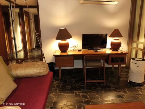 a room with a desk with a computer and two lamps at The Sky Imperial Aarivaa Luxury Stays in Rajkot