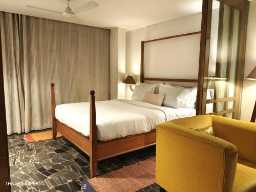 The Sky Imperial Aarivaa Luxury HomeStay في راجكوت: غرفة نوم بسرير واريكة وكرسي