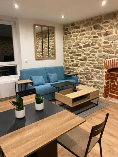 - un salon avec un canapé bleu et un mur en pierre dans l'établissement Quimperco, à Quimper