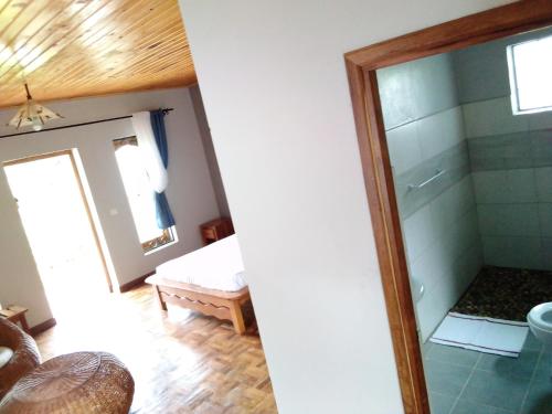 ein Bad mit einer Dusche und einem Spiegel in der Unterkunft Andasibe Sifaka Lodge in Andasibe
