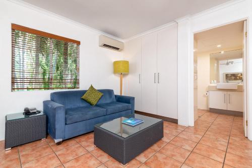 a living room with a blue couch and a table at Paradise On The Beach Resort in Palm Cove
