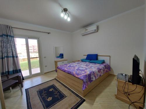 ein Schlafzimmer mit einem Bett und einem TV. in der Unterkunft Chalet Rosana Resort الساحل الشمالى in Dawwār al Ḩajj Aḩmad