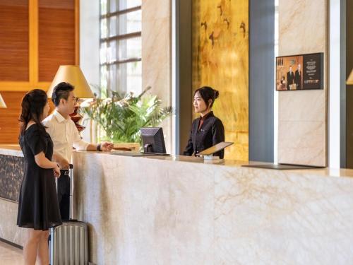 a group of people standing at a reception desk at Dongguan Forum Hotel and Apartment - Former Pullman hotel Dongguan Forum in Dongguan