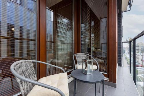a balcony with a table and chairs and windows at Siedmiogrodzka Apartment with Balcony & Parking Warsaw Wola by Renters in Warsaw
