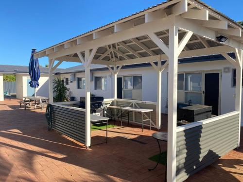 a white pergola on a patio with a table at API Pelican Beach Front Apartments Kalbarri in Kalbarri
