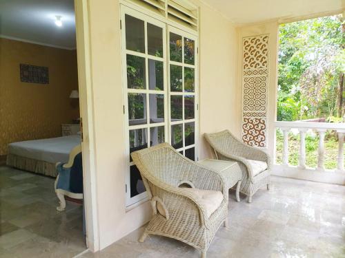 um quarto com cadeiras de vime, uma cama e janelas em Hotel Toraja Prince em Tobonga