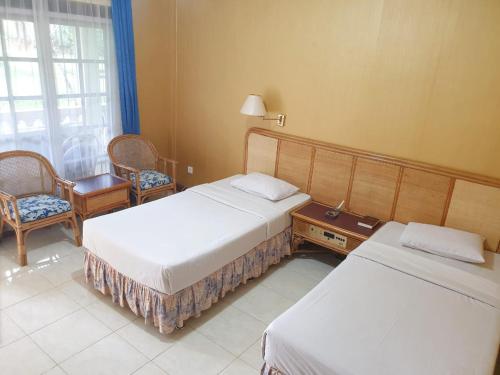 um quarto de hotel com duas camas e uma mesa e cadeiras em Hotel Toraja Prince em Tobonga