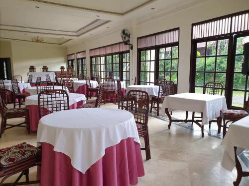 uma sala de jantar com mesas e cadeiras brancas e janelas em Hotel Toraja Prince em Tobonga