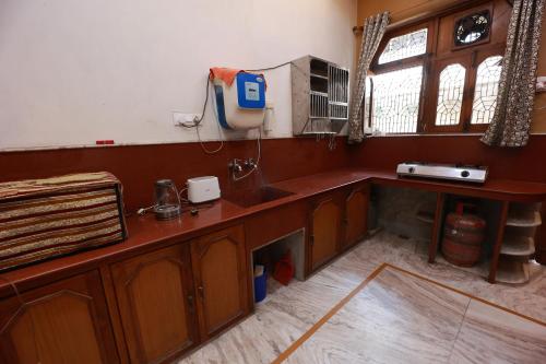 a kitchen with wooden cabinets and a sink and a window at Kapoor Sahab Homestay : it's a home away from home. in Varanasi