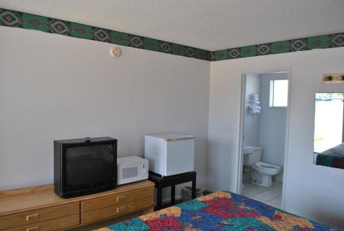 a bedroom with a bed and a tv and a bathroom at Travel Inn Motel Michigan City in Michigan City