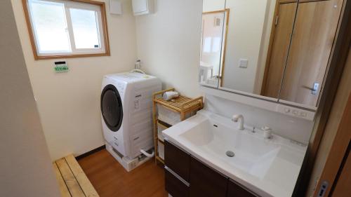 La salle de bains est pourvue d'un lavabo et d'un lave-linge. dans l'établissement Oak Village, à Hakuba