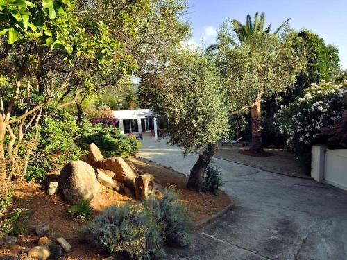 un giardino con alberi e rocce e un edificio di Villa contemporaine climatisée, vue mer exceptionnelle, à quelques mètres de la plage a Pietrosella