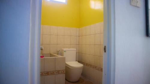 a bathroom with a toilet and a yellow wall at Omah Bagelen Homestay in Bagelen