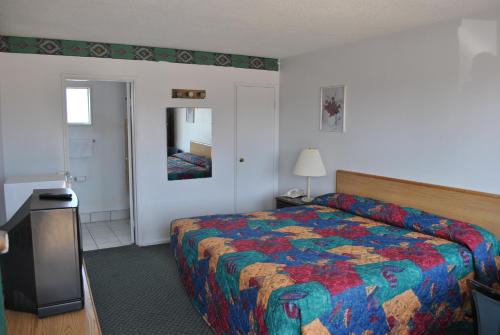 - une chambre d'hôtel avec un lit et un miroir dans l'établissement Travel Inn Motel Michigan City, à Michigan City