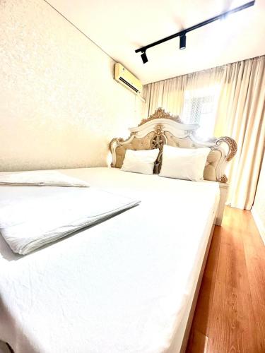- une chambre avec un lit blanc et du parquet dans l'établissement Сатпаева 13 двухкомнатная квартира в центре города, à Atyraū