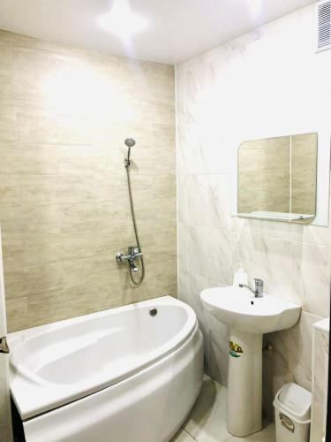La salle de bains est pourvue d'une baignoire blanche et d'un lavabo. dans l'établissement Сатпаева 13 двухкомнатная квартира в центре города, à Atyraū