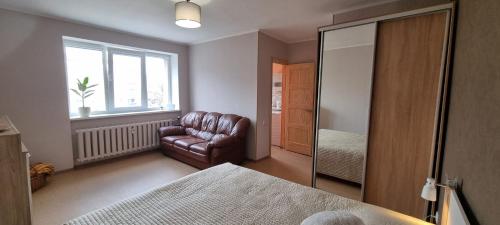 een slaapkamer met een leren stoel en een spiegel bij Ukstiņa Holiday apartment in Liepāja