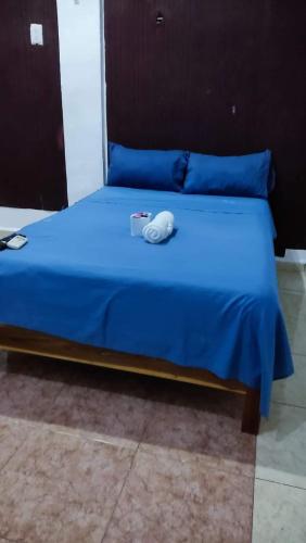 Una cama con una manta azul y un objeto blanco. en Ángel, en Campeche