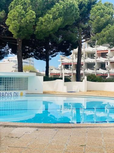 une piscine devant un immeuble avec des arbres dans l'établissement Le Studio, à La Grande Motte