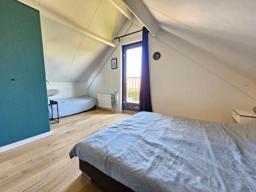 ein Schlafzimmer mit einem Bett und einem großen Fenster in der Unterkunft 7 person House with garden, firepit, swimming lake, hammock, child friendly, in- and outside playground, slide, and great coffee in Ewijk
