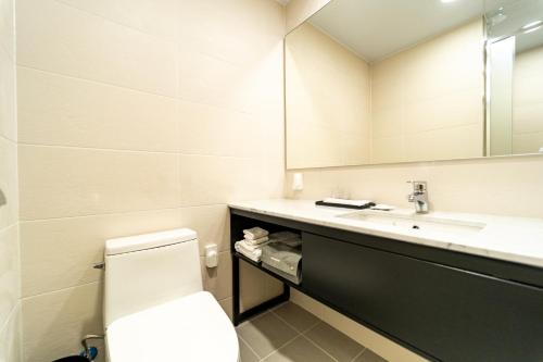 a bathroom with a toilet and a sink and a mirror at Gangneung PINEART Label in Gangneung