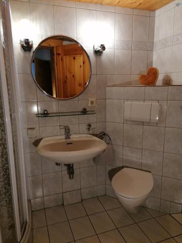 a bathroom with a sink and a toilet and a mirror at Ferienwohnungen Kail Thomas in Obsteig