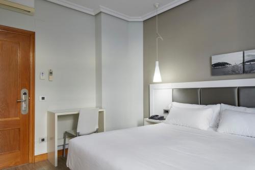 a bedroom with a white bed and a wooden door at Pensión Alemana in Donostia-San Sebastián