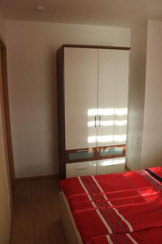 Schlafzimmer mit einem roten Bett und einem Schrank in der Unterkunft Ferienwohnung Athena in Pirna