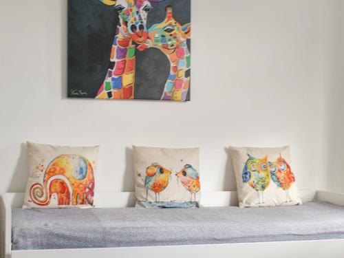 a painting of a giraffe and four pillows on a bed at High Street Apartment in Kessingland
