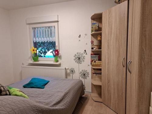 ein Schlafzimmer mit einem Bett und einem Fenster mit Blumen in der Unterkunft gemütlicher Bungalow am Rand der Dübener Heide 