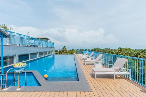 a swimming pool with lounge chairs on a deck at De Mandarin Candolim Beach Goa in Candolim